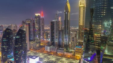 Financial center of Dubai city with luxury skyscrapers day to night transition , Dubai, United Arab Emirates. Aerial view with parking and towers rooftops