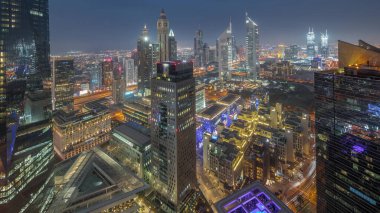 Panorama of futuristic skyscrapers after sunset in financial district business center in Dubai on Sheikh Zayed road day to night transition . Aerial view from above with museum