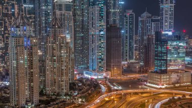 Aerial view on a big highway intersection night  in Dubai Marina with skyscrapers around, UAE. Cars traffic view from JLT district. Illuminated towers with light in windows