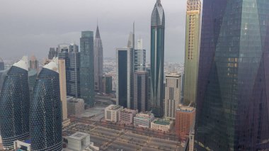 Financial center of Dubai city with illuminated luxury skyscrapers night to day transition , Dubai, United Arab Emirates. Aerial view with parking and towers rooftops