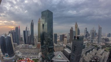 Panorama of futuristic skyscrapers with sunset in financial district business center in Dubai on Sheikh Zayed road . Aerial view from above with orange cloudy sky