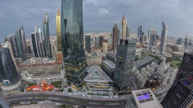 Panorama of futuristic skyscrapers in financial district business center in Dubai with road traffic night to day transition . Aerial view from above with illuminated towers during sunrise