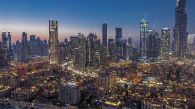 Close up view to Dubai's business bay towers aerial day to night transition . Rooftop view of some skyscrapers and new towers under construction after sunset