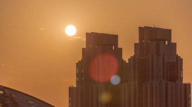 Sunset over Dubai international financial center skyscrapers aerial . Sun goes down behind tall towers and orange sky on a background