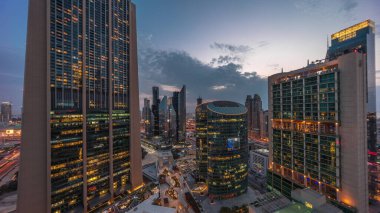 Dubai international financial center skyscrapers aerial day to night transition . Illuminated towers with promenade panoramic view from above after sunset