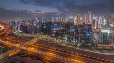 Skyline with modern architecture of Dubai business bay towers and downtown skyscrapers day to night transition . Aerial view with canal and construction site after sunset