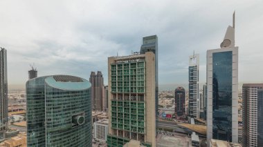 Panorama showing Dubai international financial center skyscrapers with promenade on a gate avenue aerial . Many office towers and traffic on a highway. Cloudy sky