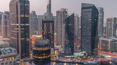 Dubai Marina Skyline with JLT district skyscrapers on a background aerial night to day transition . Illuminated towers with glass surface before sunrise