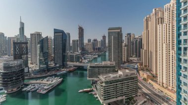 Panorama showing aerial view to Dubai marina skyscrapers around canal with floating boats and jlt with jbr districts . White boats are parked in yacht club
