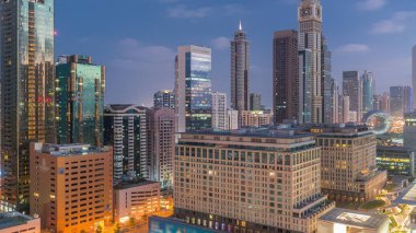 Dubai International Financial district night to day transition . Aerial view of business office towers before sunrise. Illuminated skyscrapers with hotels near downtown