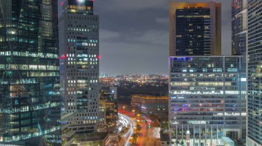 Tüm gece boyunca Dubai Uluslararası Finans Bölgesi. Yol trafiği ve Deira bölgesinin arka planında iş merkezlerinin hava görüntüsü. Işıklar sönerken aydınlatılmış gökdelenler