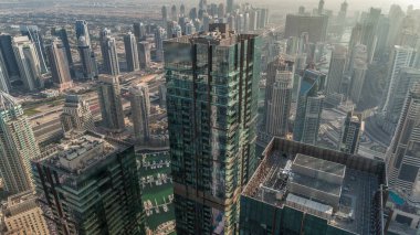 Dubai Marina ve JLT bölgesinde gökdelenler arasında trafik var. Modern kuleler ve gölgeli inşaat alanı akşama kadar hızla ilerliyor.