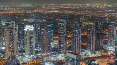 Dubai marinası kuleleri ve JLT bölgesini aydınlatmış ve metro istasyonu yakınlarındaki Sheikh Zayed yolunda trafik varmış. Yukarıdan aşağıya bak, gökdelenler çatılar, Birleşik Arap Emirlikleri.