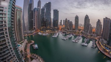 Dubai marina tallest skyscrapers and yachts in harbor aerial night panoramic before sunrise. View at apartment buildings, hotels and office blocks, modern residential development of UAE