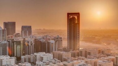 Sunrise over skyscrapers in Barsha Heights district and low rise buildings in Greens district aerial . Dubai skyline with orange sky at morning with desert on a background