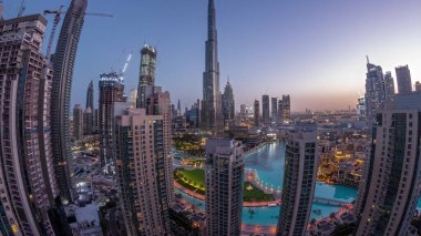 Panorama of Dubai Downtown cityscape with tallest skyscrapers around aerial night to day transition . Construction site of new towers and busy roads with traffic from above