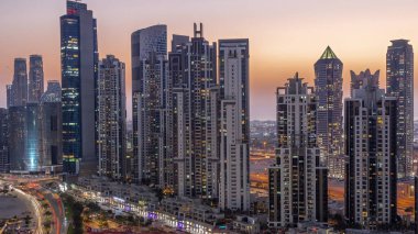 Business Bay hava sahasında modern kuleleri olan körfez bulvarı, gündüzden geceye geçiş, Dubai, BAE. Gün batımından sonra gökdelenler