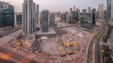 Business Bay Dubai illuminated skyscrapers with water canal aerial night to day transition panoramic . Mixed use development with residential and office towers sharing the footprint equally