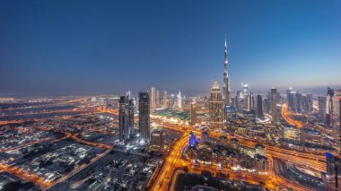 Aerial view of tallest towers in Dubai Downtown skyline and creek area day to night transition . Financial district and business area in smart urban city. Skyscraper and high-rise buildings