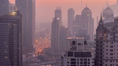 Dubai Marina and Media City districts with modern skyscrapers and office buildings aerial night to day transition . Traffic on overpass and road intersection near yachts in harbor
