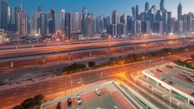 Dubai marinası, gün doğumundan önce gece gündüz en yüksek gökdelen bloğu. JLT bölgesinden apartman binalarına, otellere ve otoyol yakınlarındaki iş kulelerine hava manzarası.