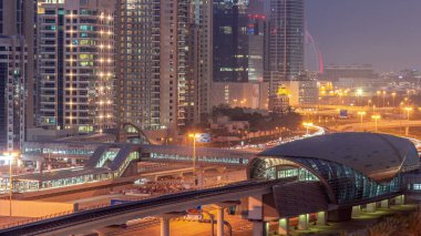 Dubai metro istasyonunun gelecekteki binası ve Dubai Marina 'daki lüks gökdelenlerin ardında günden geceye geçiş. Şeyh Zayed karayolu, Birleşik Arap Emirlikleri 'nde trafik