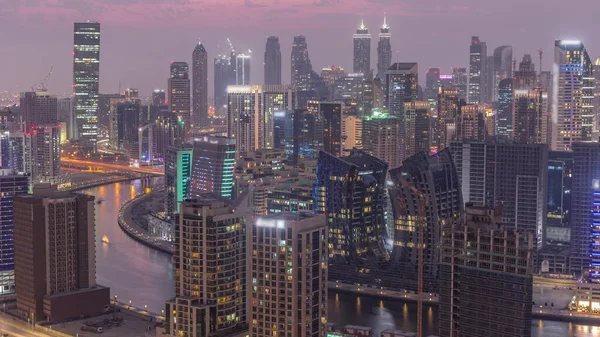 天际线与现代建筑迪拜商厦塔楼日夜不停的转换 日落后有运河和建筑工地的空中景观 — 图库照片