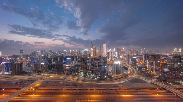 Panoramic skyline of Dubai with business bay and downtown district and traffic on al khail road night. Aerial view of many modern skyscrapers with colorful clouds after sunset. United Arab Emirates.