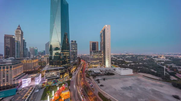 Dubai International Financial district day to night transition  with traffic on a street. Panoramic aerial view of business office towers after sunset. Skyscrapers near downtown