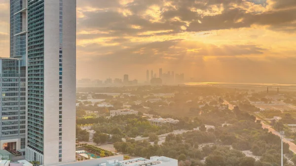 Sunrise over garden in Zabeel district with skyscrapers on a background aerial  in Dubai, UAE. Orange clouds on the sky with rays of sun light