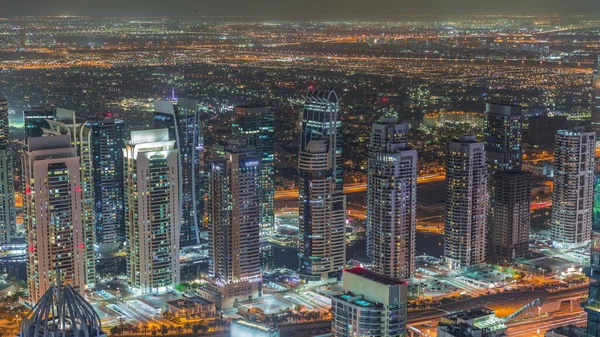 ドバイマリーナは 地下鉄駅の夜近くのシェイク ザイド道路の交通量でタワーとJlt地区を照らしました 高層ビルの屋根 アラブ首長国連邦で上から見下ろす — ストック写真