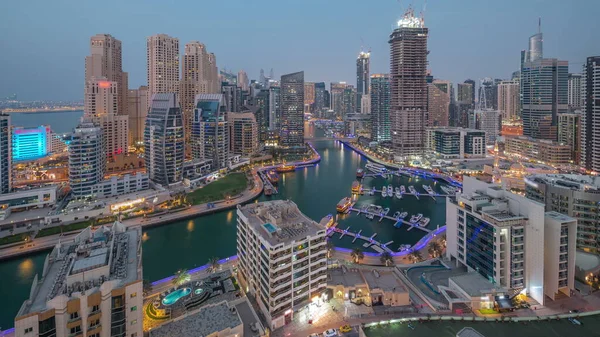 stock image Dubai Marina with several boat and yachts parked in harbor and skyscrapers around canal aerial day to night transition . Towers of JBR district and construction site with cranes