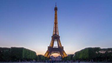 Eyfel Kulesi 'nden geceye geçiş zamanı şelale suyundaki yansıma ve Paris, Fransa' da güneş battıktan sonra Champ de Mars 'ın çimlerinde oturan insanlar.