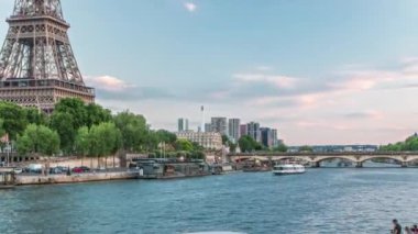 Eiffel Kulesi ve Jena Köprüsü, Fransa, Paris 'ten Paris' e geçiş zamanı olan Seine Nehri üzerinde. Nehirde gemi ve gün batımından sonra suda yansımalar.