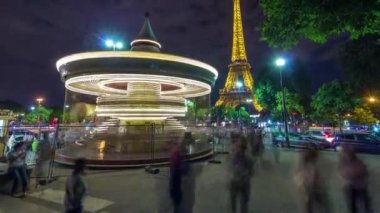 Paris, Eyfel Kulesi 'nin yakınındaki aydınlık klasik atlıkarınca. İnsanlar parkta geziniyor.