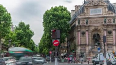 Saint-Michel Meydanı 'nın tarihi çeşmeli sokak manzarası, Paris. Arabalar ve insanlarla kavşakta trafik vardı. Yaz gününde bulutlu bir gökyüzü