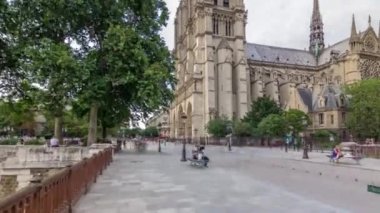 Notre-Dame de Paris zaman atlaması. Fransa, Paris 'teki Cite Adası' ndaki ortaçağ Katolik katedrali. Gün batımından önce Çifte Köprü 'den görüntü. Yürüyen turistler. Yaz gününde bulutlu bir gökyüzü