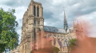 Notre-Dame de Paris zaman çizelgesi. Fransa, Paris 'teki Cite Adası' ndaki ortaçağ Katolik katedrali. Gün batımından önce Double Bridge 'den yan görüntü. Yürüyen turistler. Yaz gününde bulutlu bir gökyüzü