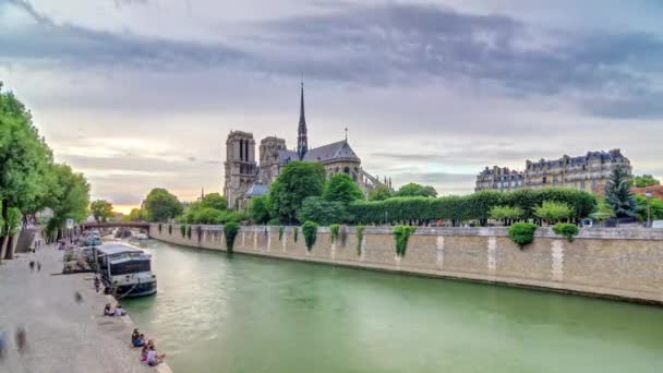 パリのノートルダム大聖堂の後ろの夕日フランスのパリでタイムラプス 大司教区の橋からの眺め ボートステーションとウォーターフロント 劇的な空とパリの建築とランドマーク — ストック動画