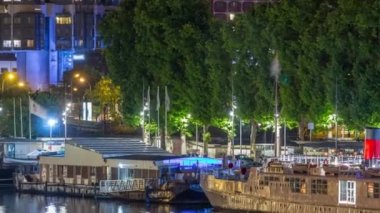 Paris 'te gece vakti gemisi olan Seine nehri, Fransa' nın Paris şehrinin rıhtım kıyısı. Mirabeau Köprüsü 'nden hava görüntüsü. Tekne istasyonu ve yeşil ağaçlar