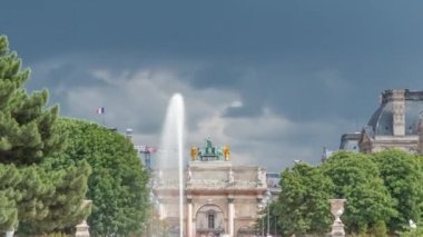 Tuileries Sarayı 'ndaki çeşmede dinlenen insanlar açık hava parkı zaman dilimi. Arka planda Arc de Triomphe du Carrousel 'e bakın. Dramatik bulutlu gökyüzü ile yaz günü sahnesi. Paris, Fransa
