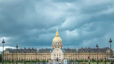 Fransa, Paris 'te Les Invalides' in önündeki trafik sıkışıklığı. Üstünde Fransız bayrağı var. Yaz gününde dramatik bulutlar. İki tarafta da sokak lambaları var.