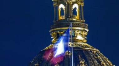 Paris, Fransa 'da gece aydınlatma saatinde Les Invalides Kubbesi. Üstünde Fransız bayrağı var. Çatıya yakın görünüm