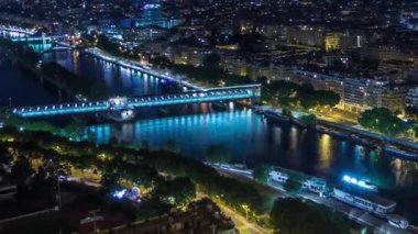 Paris Şehri 'nin ve Eiffel Kulesi gözlem güvertesinin tepesindeki Seine nehri üzerindeki köprülerin uçuş zamanı. Akşam aydınlatması.