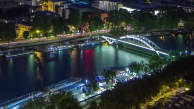 Paris City ve Seine nehrinin gece görüş açısı Eyfel Kulesi gözlem güvertesinin tepesinden geçen teknelerle dolu. Akşam aydınlatması. Yollarda trafik