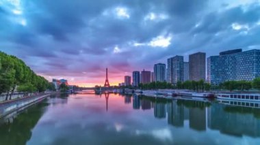 Eyfel Kulesi, Seine Nehri 'nde ve Fransa' nın Paris şehrinde teknelerle gün doğumu zamanı. Mirabeau Köprüsü 'nden gökyüzü dramatik bir şekilde görünüyor. Modern binalar ve yol trafiği. Özgürlük Anıtı