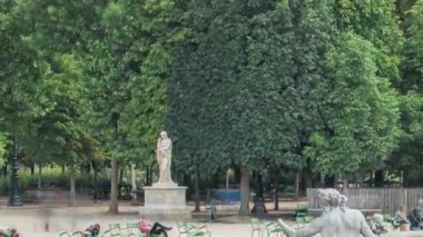 Tuileries Sarayı 'ndaki çeşmede yürüyen ve dinlenen insanlar açık hava parkı zaman aralığında. Arka planda yeşil ağaçlar. Bulutlu mavi gökyüzü ile yaz günü sahnesi. Paris, Fransa