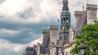 The Hotel de Ville Belediye Binası 'nın mimarisi. Paris şehrinin yerel yönetimine ev sahipliği yapan üst zaman kulesinde Fransız bayrağı var. Yaz günü bulutlu bir gökyüzü. Görüntüyü kapat