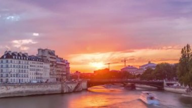Günbatımında Le Pont DArcole Köprüsü 'nde insanlar ve tekneler zaman ayarlı, Paris, Fransa, Avrupa. Yaz günü Seine nehrinin yansımasıyla renkli bir gökyüzü. Arkaplanda vinçleri olan inşaat