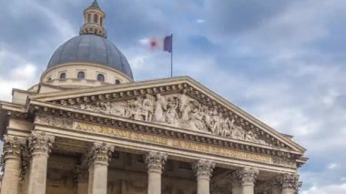 Ulusal panteon binası zaman atlaması, sokak manzarası ve yürüyen insanlar. Sokakta trafik, yaz gününde bulutlu hava. Üstte bayrak var. Paris, Fransa